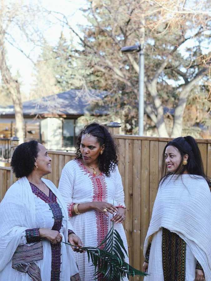 Three women chatting, one holding a palm branch