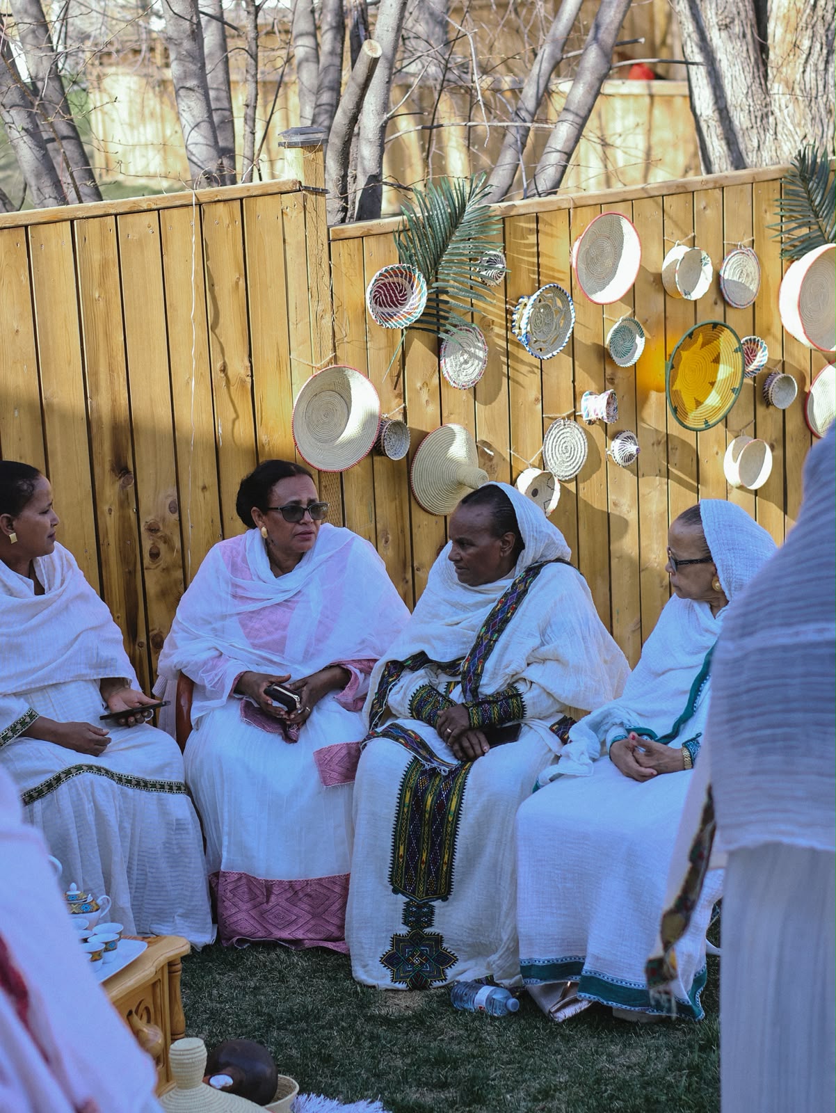 Group of women in white habesha dresses seated together, talking