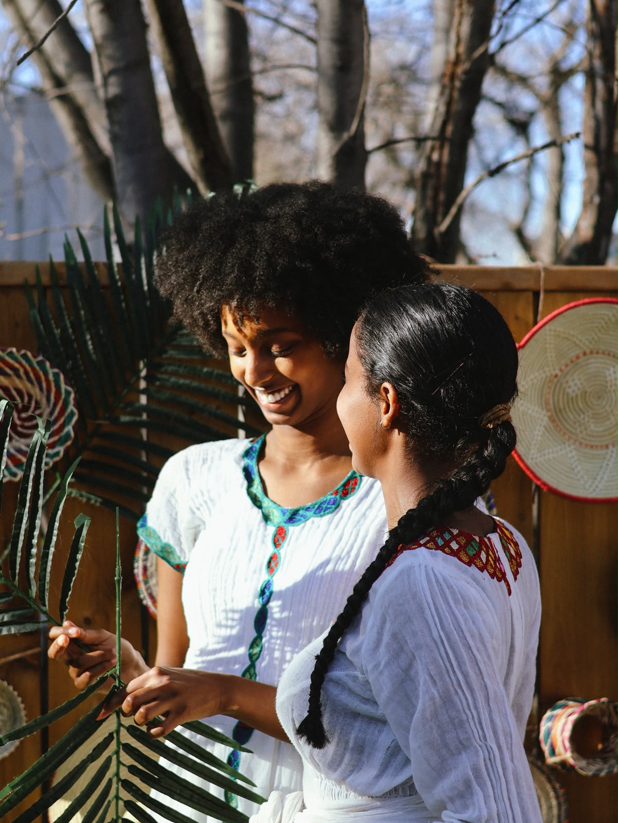 Two young women in embroidered white dresses laughing together
