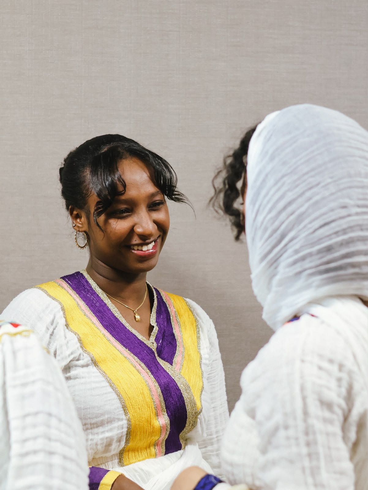 Two women in colorful embroidered dresses talking closely