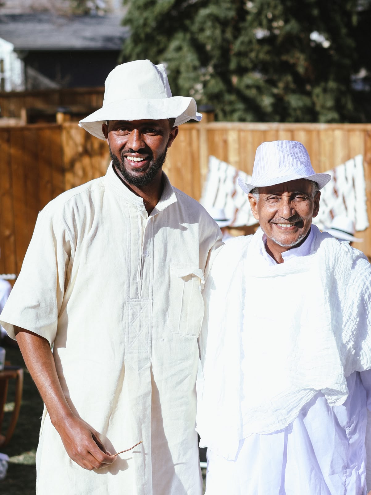 Two men in white habesha clothing smiling together