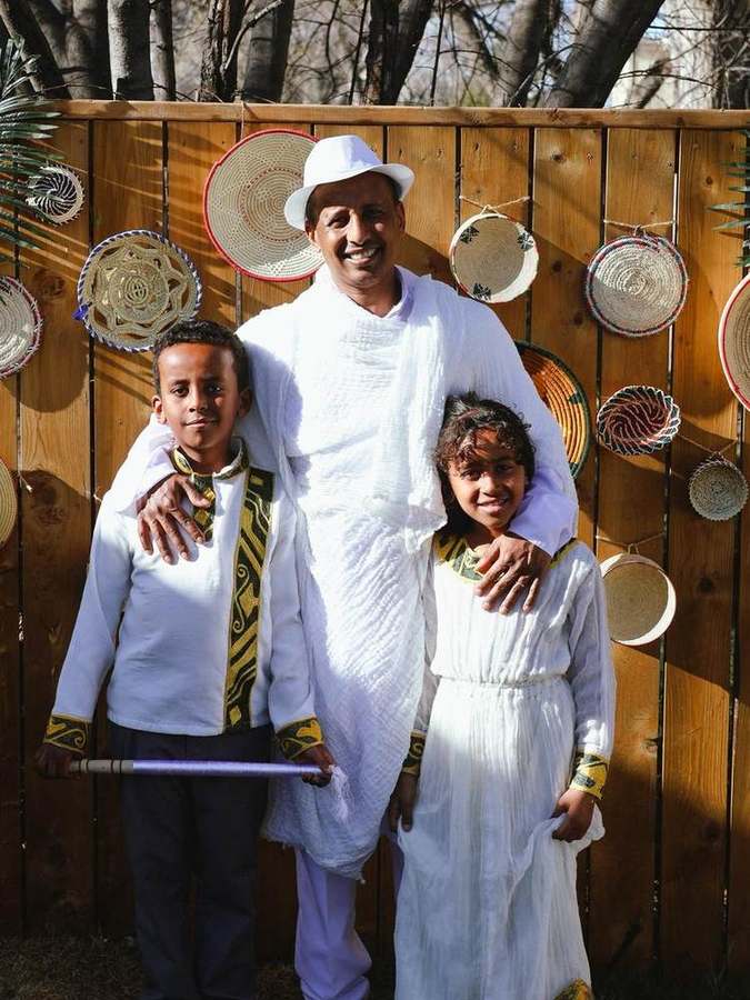 A father and his two children in front of the woven basket display