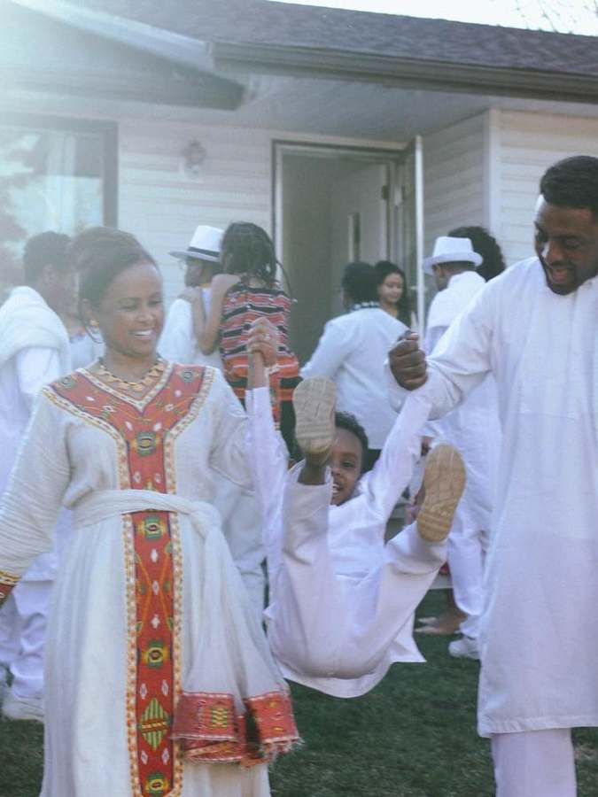 A family walking together, swinging a child by the hands