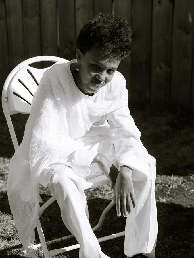 A young man seated, smiling at the camera