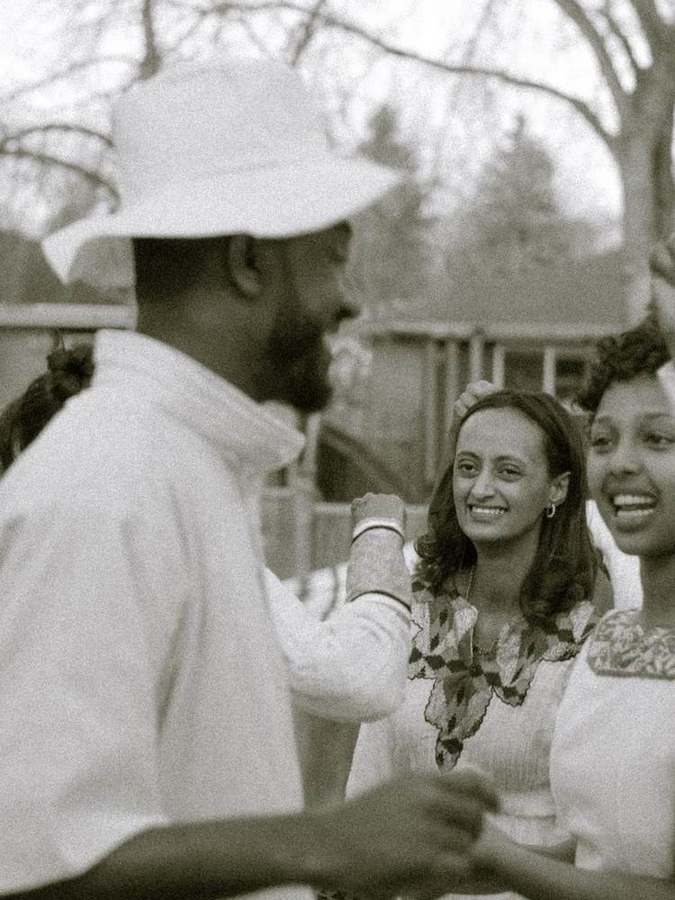 A man in a white hat greeting a friend with a fist bump