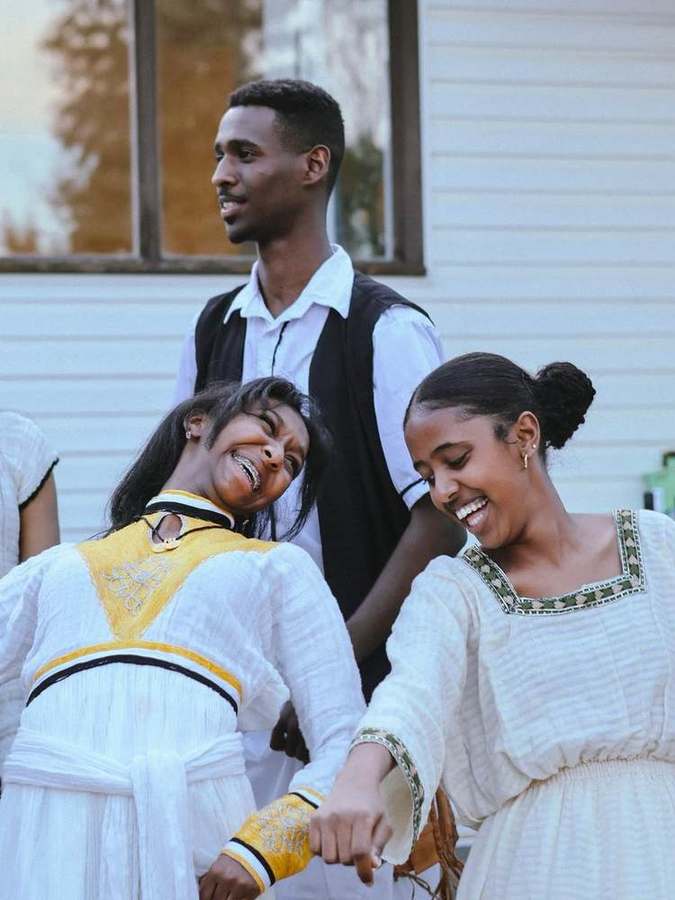Three friends laughing together mid-dance