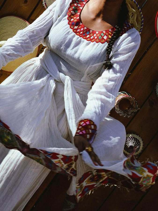 Overhead view of a woman dancing in a white dress with an embroidered scarf