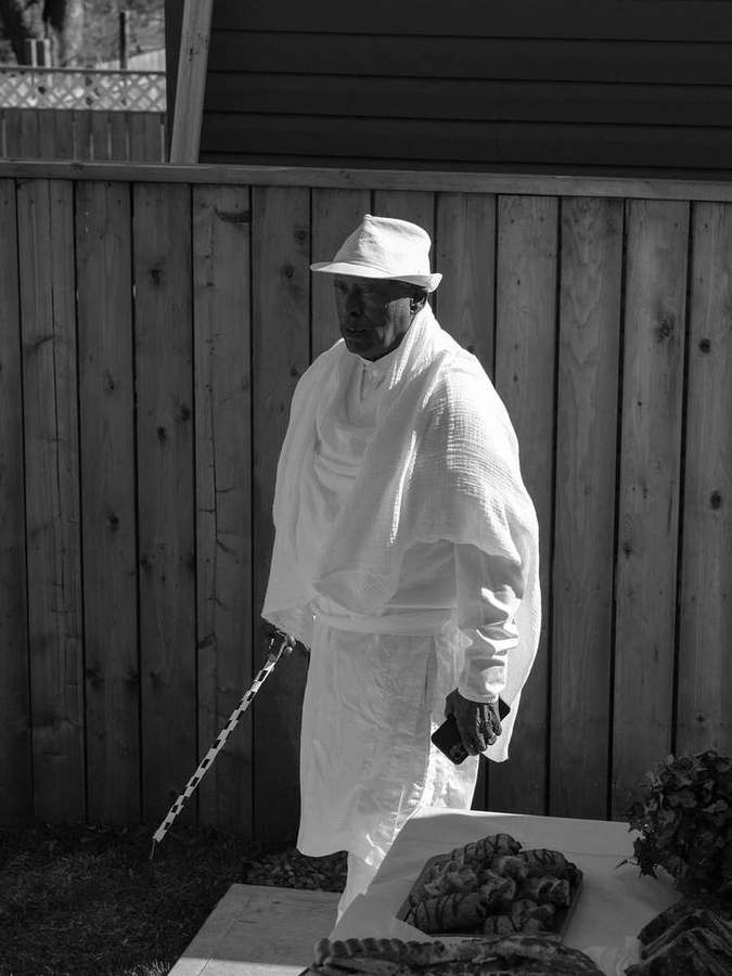 An elder in a white hat and shawl holding a cane