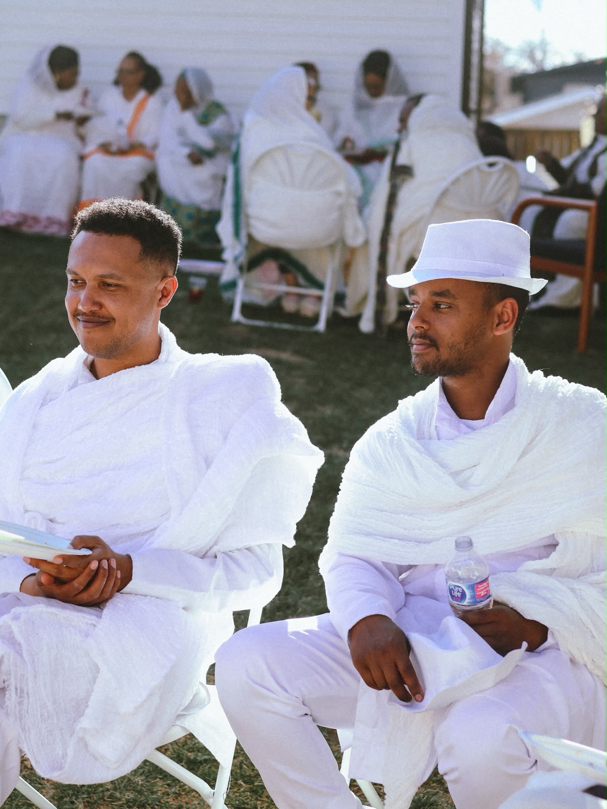 Two men in white seated together during the gathering